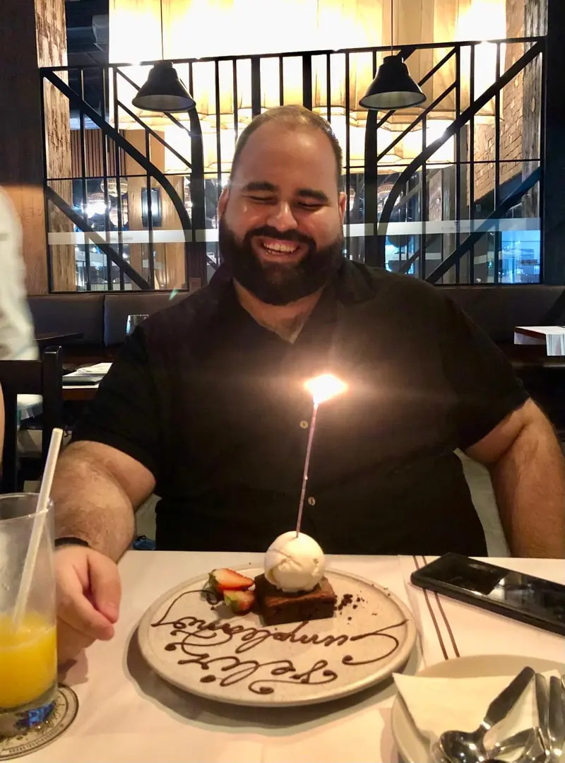 Renzo at his birthday dinner, March 2024, smiling with a candle